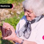 Idosa feliz mexendo na carteira pós benefícios do INSS.