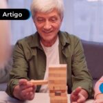 Idosos sentados a mesa praticando jogos recreativos.