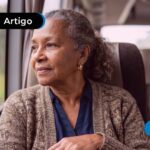 Idosa sentada em um ônibus olhando para a janela.