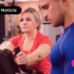 Mulher treinando em academia com personal.