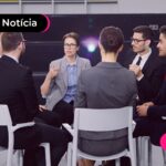 Pessoas com trajes sociais sentados em uma roda de cadeiras.