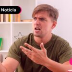 Homem sentado em uma cadeira, segurando um celular.