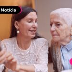 Mulher e idosa sentadas olhando para um celular.