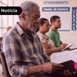 Idoso sentado em uma cadeira segurando uma agenda.