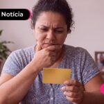 Mulher olhando para um papel com feição expressando dúvidas.