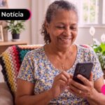 Idosa sentada na cadeira olhando para o celular.
