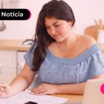 Mulher jovem anotando despesas do filho.
