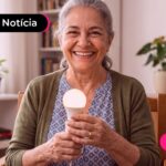 Idosa sorrindo para a foto e segurando uma lâmpada.