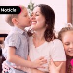 Mãe e seus filhos sentados no sofá da sala.