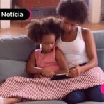 Mãe e filha juntas sentadas no sofá.