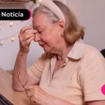 Idosa sentada na sala expressando preocupação.