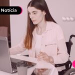 Jovem de cadeira de rodas olhando para o notebook.