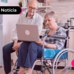 Um casal de idosos sentados olhando para um notebook.