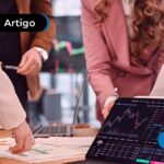 Pessoas reunidas em volta de um tablet que mostra alguns dados.