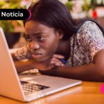 Jovem mexendo no computador com expressão triste.