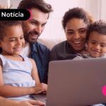 Família reunida no sofá da sala olhando para um notebook.