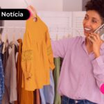 Mulher em pé segurando uma blusa amarela.