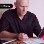 Homem com traje social em uma sala reservada olhando para um tablet.