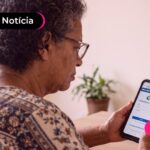 Idosa de vestido estampado olhando para o celular.