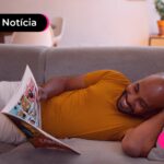 Homem deitado no sofá olhando para uma revista.