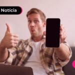 Homem fazendo joinha com a mão e mostrando o celular.
