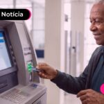 Idoso segurando um cartão em frente ao caixa eletrônico.
