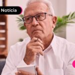 Idoso de óculos sentado no sofá expressando estar pensativo.