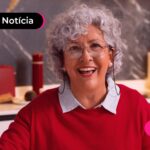 Idosa de camiseta vermelha sorrindo para a foto.