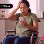 Mulher em cadeira de rodas preocupada ao olhar para o celular.