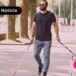 Homem passeando com seu cachorro e segurando uma bengala.