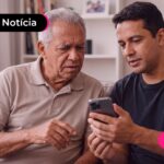 Homem mostrando algo no celular para um idoso.