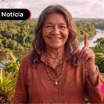 Idosa levantando o dedo pra cima e com sorriso no rosto.