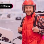 Entregador com mochila nas costas sorrindo para a foto.