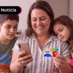 Mãe com seus filhos sentados no sofá olhando para o celular juntos.