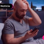 Homem sentado no sofá olhando para o celular.
