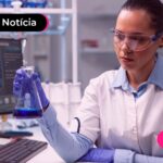Mulher trabalhando em um laboratório segurando um frasco de vidro.