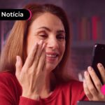 Mulher de camiseta vermelha sorrindo para o celular.